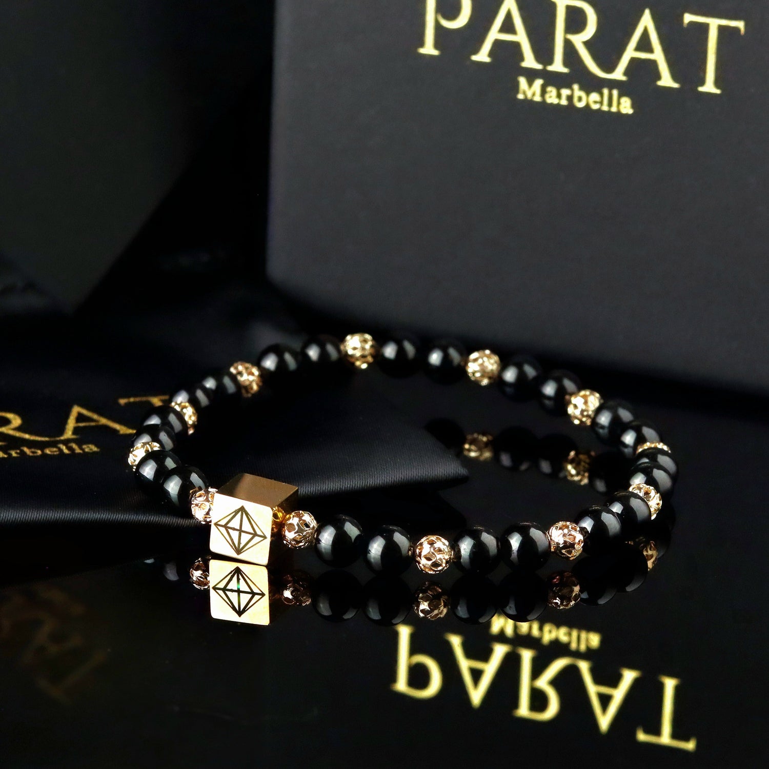 Black tourmaline with 14K gold beaded men bracelet on a black surface with 'Parat Marbella' branding.