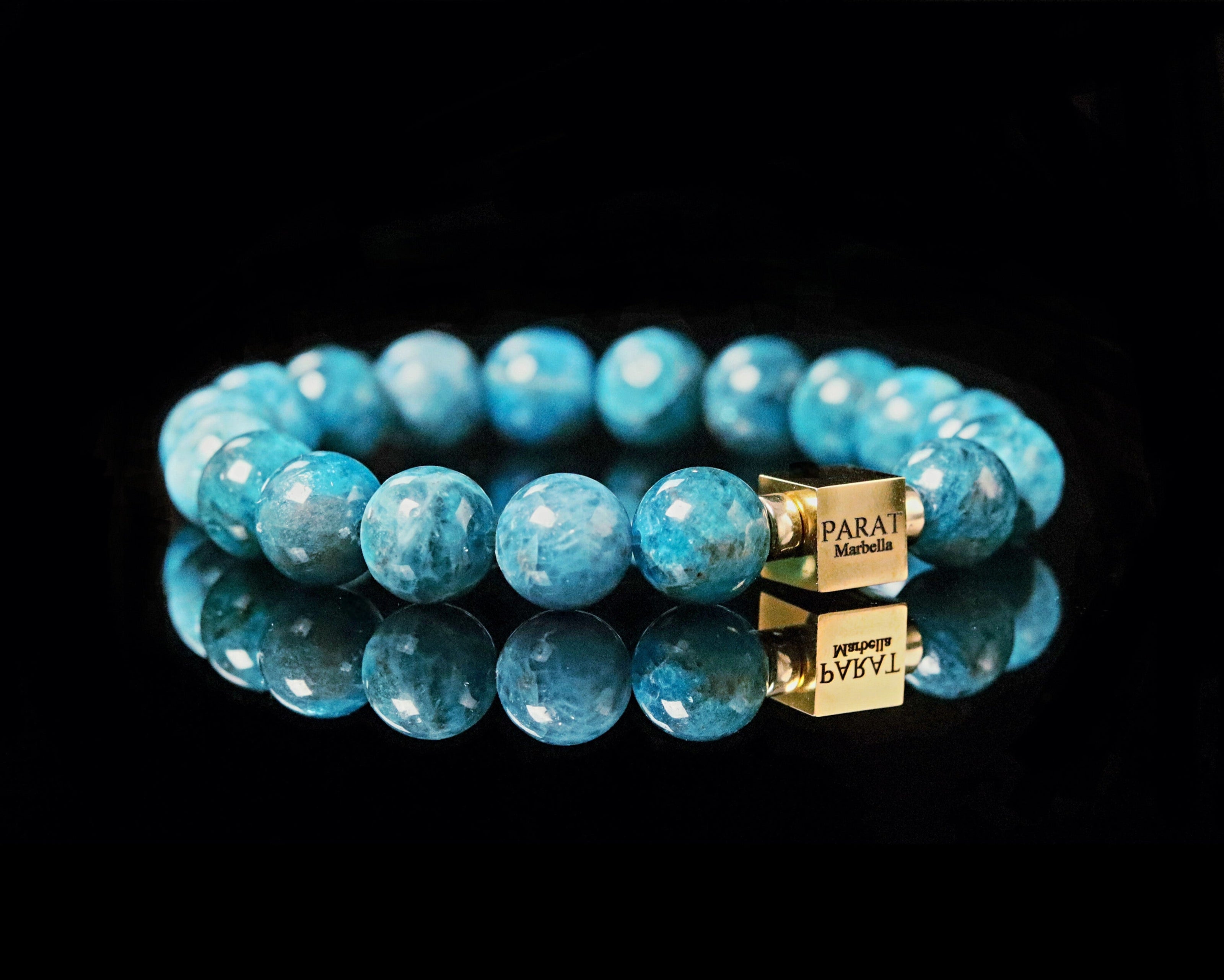 Blue Apatite gemstone beaded bracelet with gold cube logo Parat Marbella on a black background